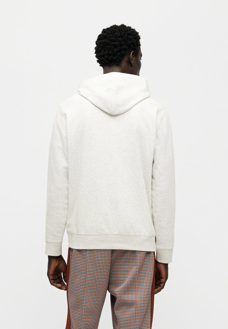 Sweat à capuche gris clair avec capuche à cordon de serrage et poignets côtelés. Associé à un pantalon à motif à carreaux. Design simple et décontracté.