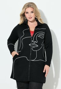 Czarna rozpinana kurtka z nadrukiem w stylu białej linii przedstawiającym twarz, posiadająca dwie przednie kieszenie i miękką fakturę. Idealna do codziennego noszenia.