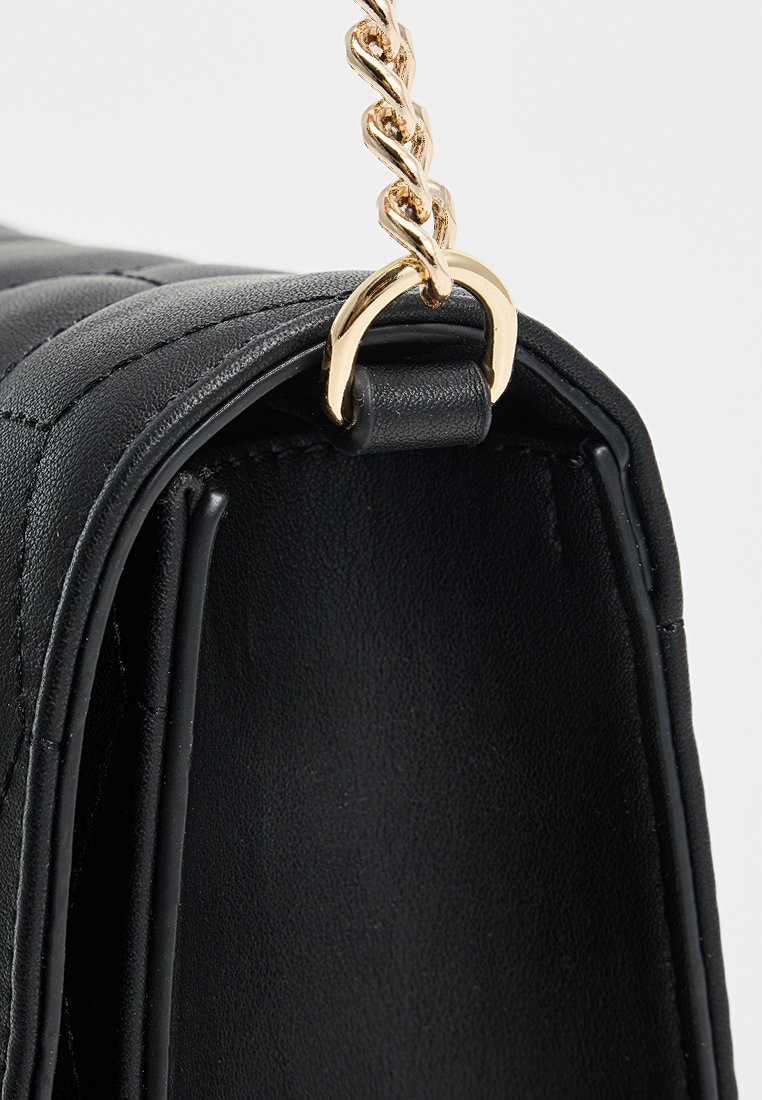Bolso de mano de cuero negro con un patrón acolchado, correa de cadena dorada y acentos de anillo metálico. El interior presenta un acabado suave sin detalles adicionales.