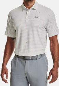 Harmaa lyhythihainen pikeepaita, jossa on teksturoitu kuosi ja pieniä oransseja yksityiskohtia. Paidassa on kaulus ja rintapielessä Under Armour -logo.