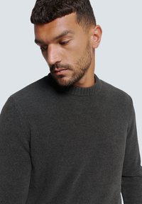 Dunkelgrauer Pullover mit rundem, geripptem Ausschnitt; strukturierter Wollstoff, taillierte Passform, leicht und mit langen Ärmeln.