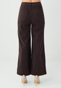 Brede bruine broek van stevig materiaal, met een hoge taille en twee achterzakken, een gladde textuur en nette stiksels.