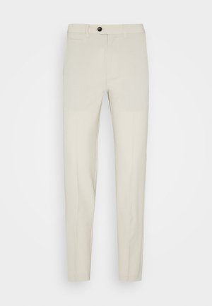 Beige Tailored-Hosen mit schmaler Passform, aus glattem Stoff, mit einer einzelnen Vordertasche und einem schwarzen Knopfverschluss.