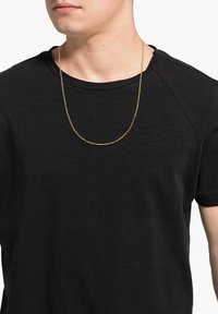 Collana in oro indossata sopra una maglietta nera a collo rotondo. La maglietta ha una texture liscia e maniche corte.