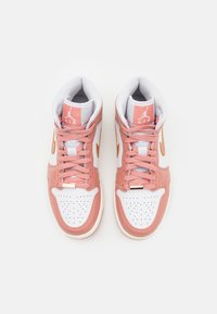 Valkoiset ja vaaleanpunaiset Air Jordan -korkeat tennarit, joissa on vaaleanpunaiset nauhat, oranssi swoosh ja Air-logo kielekkeellä, nähtynä ylhäältä päin.