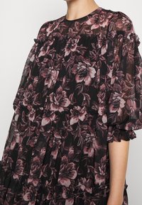 Robe noire à fleurs avec tissu transparent, encolure froncée et poignets à volants, présentant un design en couches et des motifs de roses roses et bourgognes.