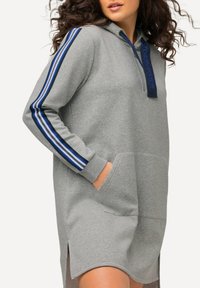 Abito felpa grigio con cappuccio realizzato in tessuto morbido, dotato di tasche laterali, dettagli con strisce blu sulle maniche e design con mezza zip.