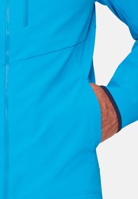 Türkiser leichter Jacke mit Reißverschluss vorne, seitlichen Taschen und marineblauen Akzenten an den Bündchen. Glatte Textur und aerodynamisches Design.