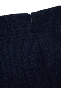 Marinefarbener, strukturiertes Gewebe mit gewebtem Muster, ausgestattet mit einem unauffälligen Reißverschlussverschluss auf der Rückseite zum Schließen.