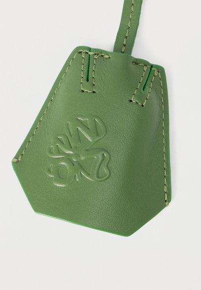Étiquette de bagage en cuir vert avec bords cousus et logo embossé en forme de trèfle à quatre feuilles avec les lettres NWSD.