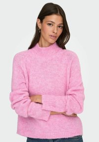 Roosa kangast kampsun kõrge kaeluse, lõtvade varrukate ja pehme, karvase tekstuuriga, millel on mugav lõige ja soonikkoes mansetid.