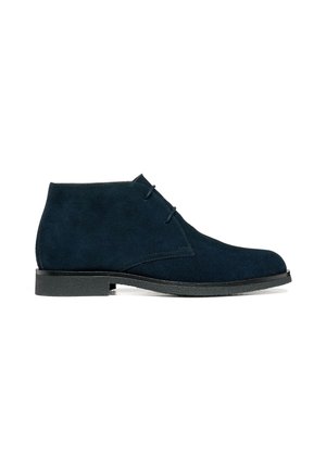 Bottine en daim bleu marine avec deux œillets, bout rond, semelle noire et coutures minimales, montrée en profil latéral sur fond blanc.