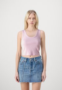 Lyserød ribbet crop top med brede stropper og en scoopudskæring, parret med en afbleget blå denimnederdel med frynset kanter og frontlommer.