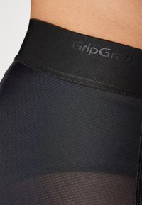 Fekete leggings, textúrált, bordázott anyagból, sima, "GripGrab" logóval domborított derékpánttal és félig átlátszó alsó résszel.