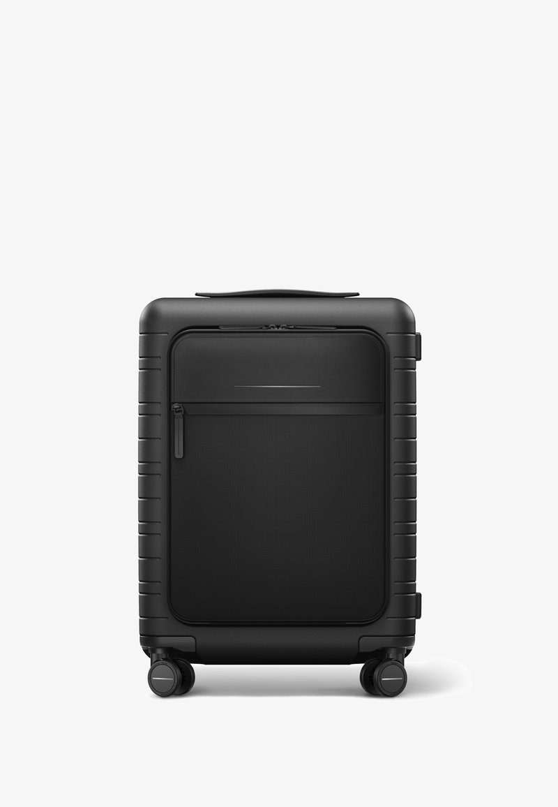 Valise rigide noire avec une finition texturée, une fermeture éclair lisse, une poche avant et quatre roues pour une mobilité aisée. Design compact.