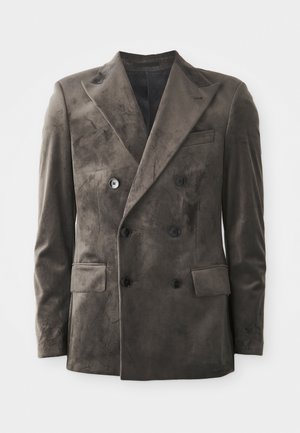 Blazer de doble botonadura en ante gris oscuro. Las características notables incluyen solapas en punta, cuatro botones y dos bolsillos frontales con una textura suave.
