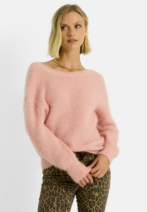 Pull en tricot rose avec un design décolleté, finition texturée et manches longues. Associé à un pantalon à imprimé animal avec une large ceinture.