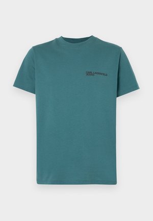 Tiso v turkizni barvi iz bombaža, z okroglim ovratnikom in kratkimi rokavi. Na levem prsnem delu je črn logotip s tekstom: "Karl Lagerfeld Jeans."