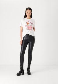 White T-shirt with red holiday graphic of a mug and gingerbread, paired with black leather skinny pants and chunky black platform shoes.