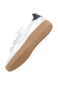 Baskets blanches avec une semelle en caoutchouc beige, dotées de bandes Velcro et d'un dessus lisse. Accent noir au niveau du talon avec le logo de la marque.