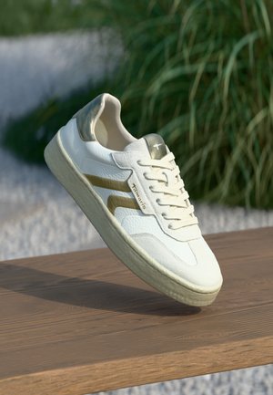 Weiße Sneakers mit einer strukturierten Oberfläche, goldenen Akzenten und flachen Schnürsenkeln, ausgestattet mit einer glatten Sohle sowie einer gepolsterten Ferse und Zunge.