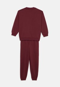 Completo felpa e jogger bordeaux, realizzato in tessuto morbido. Maniche lunghe con polsini a costine, vita elastica e polsini aderenti alla caviglia.