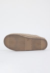Slipperzool met een getextureerd, zigzag profiel en een pluche stof bovenkant zichtbaar langs de randen, op een effen witte achtergrond.