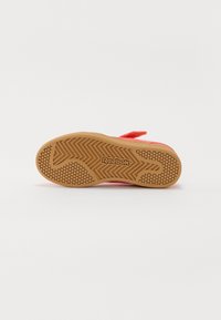 Reebok tenisica s potplatom koji se sastoji od teksturiranog, protukliznog gumenog materijala, u smeškastoj boji s ribljom kostom i brend logom.