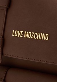 Rudas dirbtinės odos kuprinė su auksiniu "LOVE MOSCHINO" užrašu. Turtinga minimaliai siuvinėta tekstūra ir glotni paviršius. Vienalytė spalva.