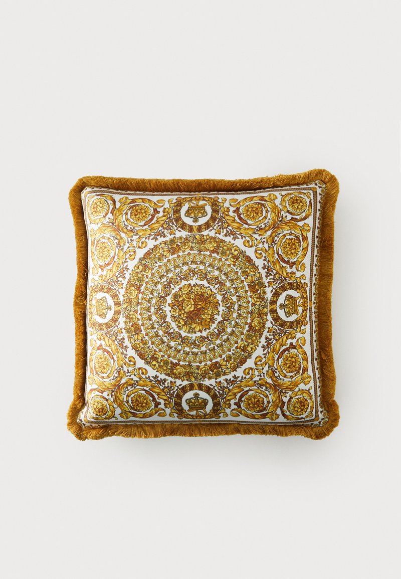 Négyzet alakú párna bonyolult arany virág- és körmintákkal fehér háttéren. Bojtos, mustár sárga szegély. Puha szövet textúra.