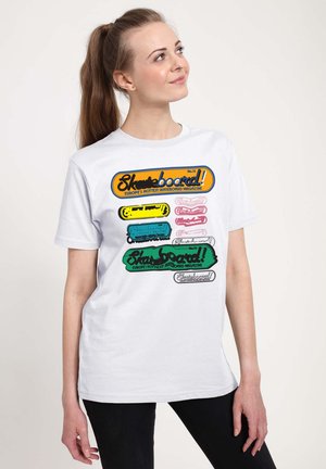 Hvid bomulds t-shirt med farverige skateboard-grafikker i orange, gul, pink, blå og grøn, med tekstelementer og forskellige designs.