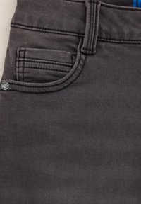 Tissu denim gris foncé avec des coutures contrastées, une petite poche avant et un bouton en métal marqué. Texture lisse avec un léger éclat.