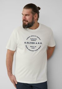 White cotton t-shirt featuring a round navy graphic print with text: "Casual Quality Supply Elevated Casual S.OLIVER A.R.R. Built to Last Work Induced Hard Wear."