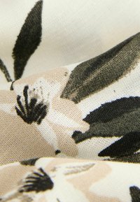 Blommönstrad tyg med krämfärgad bakgrund, som har svarta och dämpade pastellblommor. Mjuk textur, fokus på veck och detaljrikedom.