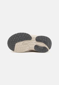 Schuhsohle mit einem strukturierten schwarzen Gummiprofil und einer beigen Zwischensohle, einschließlich gemusterter Griffe und einer abgerundeten Ferse für besseren Halt.