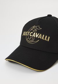 Crni bejzbol kapa s zlatnim logotipom "JUST CAVALLI" i zlatnim detaljem na obodu. Izrađena od teksturiranog materijala, s zakrivljenim vizorom.