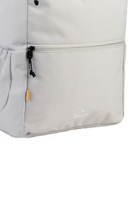 Grauer Rucksack aus strukturiertem Stoff, mit einer Reißverschlusstasche mit einem schwarzen Zipper, einem kleinen orangefarbenen Akzent und weißem Markenlogo an der Seite.