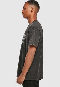 Svart oversized bomull T-skjorte med rund hals. Har hvit tekst på fronten. Korte ermer og en avslappet passform. Falmet tekstur.