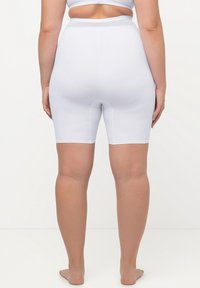 Shorts bianchi a vita alta con una superficie liscia, dal design lungo fino al ginocchio e una silhouette aderente. Presentano una ampia vita elastica.