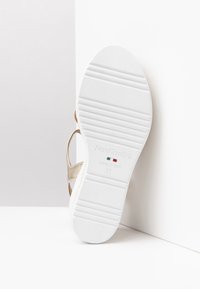 White shoe sole with ridges, gold suede accents and "NeroGiardini" branding; made in Italy, size 37, featuring a smooth, flat texture.