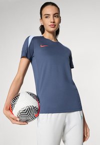 Navy Nike athletic shirt with light blue accents, short sleeves, and a smooth texture, held with a black and white patterned soccer ball.