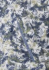 Witte stof met een groen en marineblauwe bladerenpatroon; heeft een blauwe rand langs de zak. Geweven, lichtgewicht, geschikt voor casual wear.