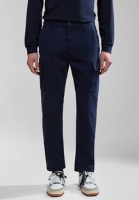 Navy blue cargo pants made of cotton. Features side pockets, a button closure, and a relaxed fit. Textured fabric with minimal stitching details.