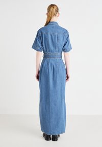 Džinsu garš kleitas ar īsām piedurknēm, jostu viduklī un aizmuguri. Izceļas ar vidēji zilu nokrāsu un gludu, nedaudz teksturētu audumu.