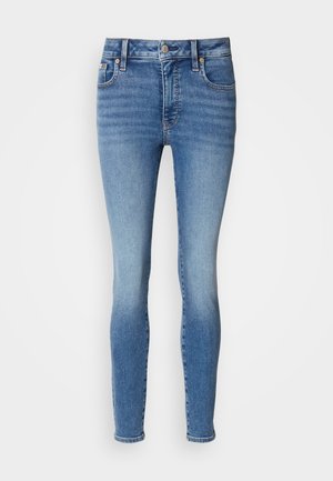 Blå stramme jeans lavet af denim med en falmet finish, som har fem lommer, bæltestropper og en knaplukning i taljen.
