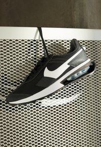 Nike sneaker featuring a black mesh upper with white accents, a padded collar, Air unit sole, and rubber outsole with textured grip.