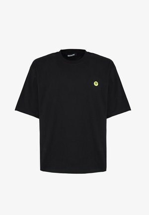 T-shirt nera in cotone con maniche corte, scollo rotondo e un piccolo logo di faccina sorridente gialla sul lato sinistro del petto.