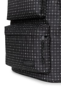 Mochila negra con un patrón de cuadrícula de puntos blancos, que cuenta con un bolsillo frontal con cremallera, tejido texturizado y parche del logo de Eastpak.