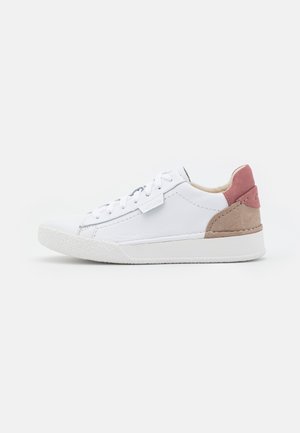 Hvid lav sneaker med hvide snørebånd, beige ruskindshæl og pink ruskindskrave, vist fra ydersiden på en ensfarvet baggrund.