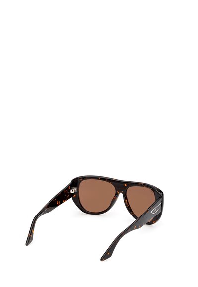 Gafas de sol con lentes teñidas de marrón, montura negra de carey y varillas anchas, inclinadas ligeramente hacia atrás sobre un fondo blanco.